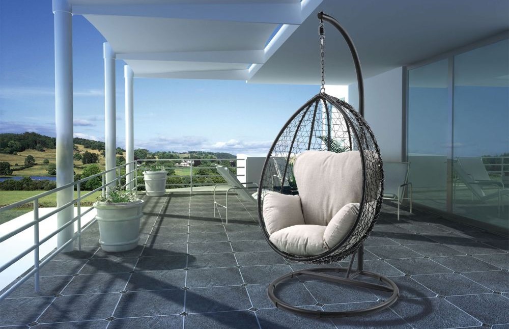 Outdoor hanging egg chair with beige cushions and a freestanding frame on a balcony