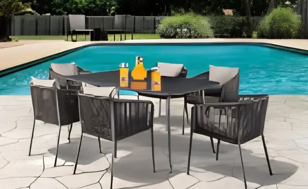 Patio furniture set with chairs and a table beside a swimming pool